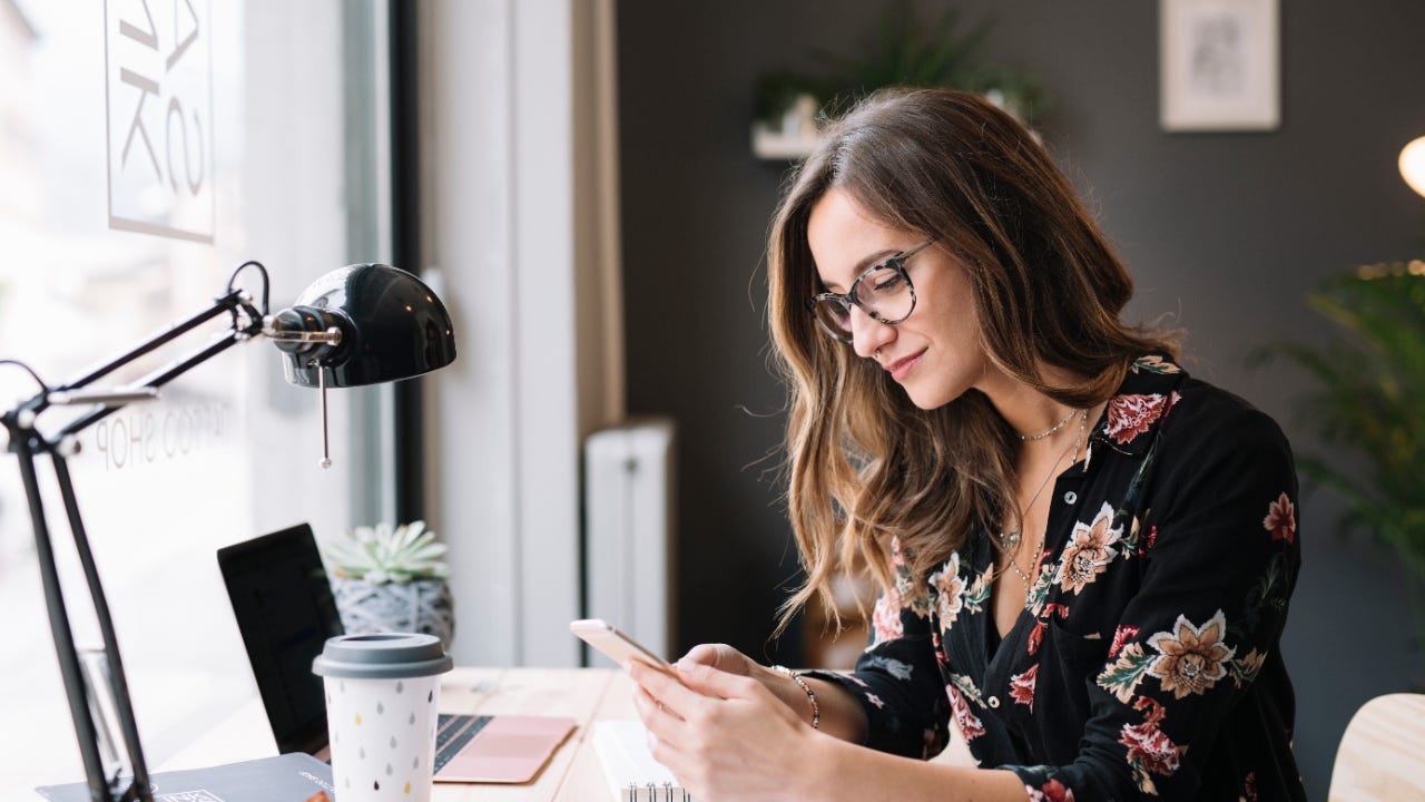 A woman looks at her phone at her desk